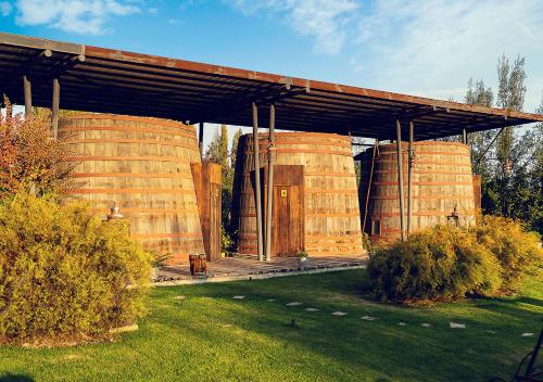 a building with two large wooden barrels in a field at Cava Colchagua Hotel Boutique in Santa Cruz