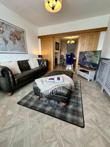 a living room with a leather couch and a flat screen tv at Luxury Pet Friendly 3 Bedroom Home with Copper Bath in Bowness-on-Windermere
