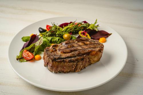 a white plate with a steak and a salad at Cava Colchagua Hotel Boutique in Santa Cruz