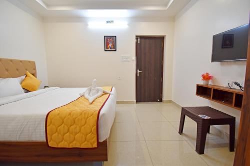 a bedroom with a bed and a television and a table at Cannan Residency in Pūrnānkuppam