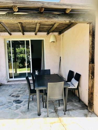 une table noire et des chaises sur une terrasse dans l'établissement Mini Villa Santa Giulia à 120m de la plage, à Porto-Vecchio
