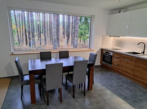 a kitchen with a dining room table and chairs at Luksusowy dom w sosnowym lesie in Płaska
