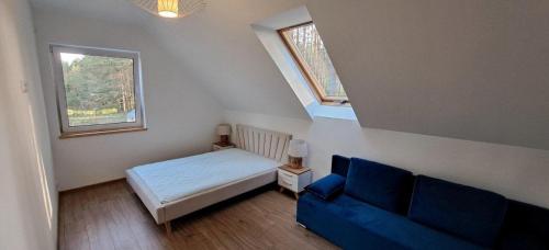 a bedroom with a bed and a blue couch at Luksusowy dom w sosnowym lesie in Płaska