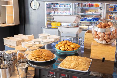 a counter with plates and bowls of bread and food at Novotel Suites Paris Montreuil Vincennes in Paris
