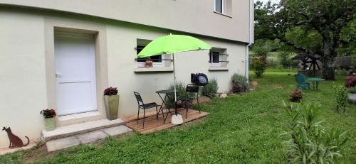 a green umbrella on a house with a table and chairs at Charmant studio Van Gogh in Chabeuil