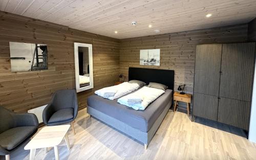 a bedroom with a bed and two chairs in it at Brygga på Dønna in Berfjorden