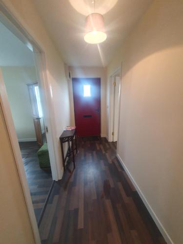 a hallway with a red door and a wooden floor at Pats Cottage in Donegal