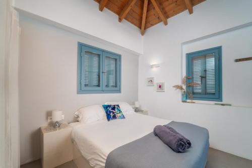 a white bedroom with blue windows and a bed at Villa Etoni, amazing sea views, infinity pool in Kalamitsi