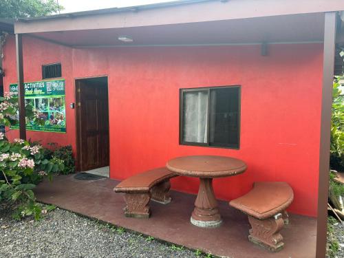 a red wall with a table and two stools at Pura Vida Aparment - Downtown La Fortuna in Fortuna