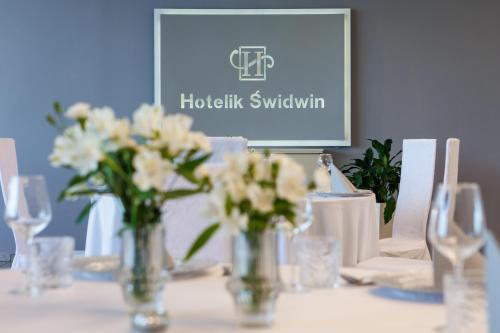 a table with vases with white flowers on it at Hotelik Świdwin in Świdwin