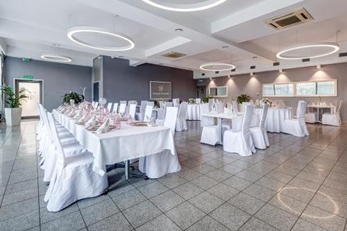 a large room with white tables and white chairs at Hotelik Świdwin in Świdwin