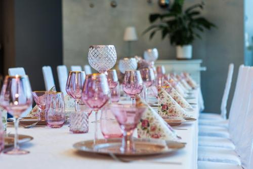 a long table with pink wine glasses on it at Hotelik Świdwin in Świdwin