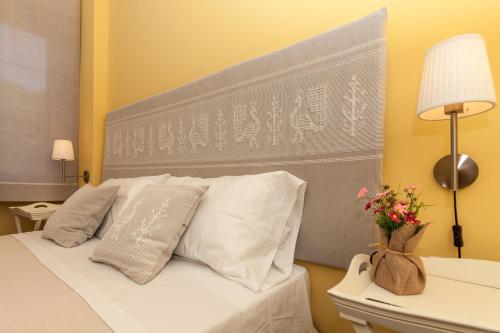 a bed with white pillows and a gray headboard at La Tuia e il Tasso in Cagliari