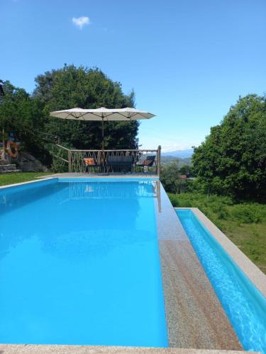 a swimming pool with a table and an umbrella at Casa de Suelas in Viana do Castelo