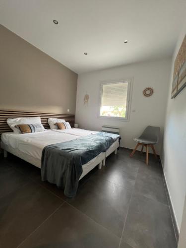 une chambre avec un grand lit et une chaise dans l'établissement Villa JOPI 3Ch piscine plage entierement climatisée, au Grau-dʼAgde