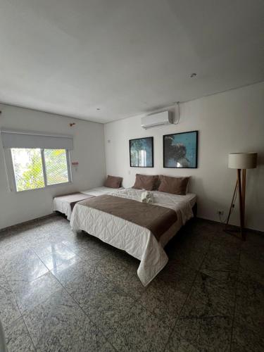 a bedroom with a large bed and two windows at Makai Hotel Boutique - Frente Mar in Guarujá