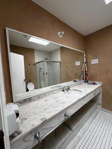 a bathroom with a large mirror and a sink at Makai Hotel Boutique - Frente Mar in Guarujá