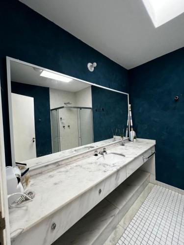 a bathroom with a sink and a large mirror at Makai Hotel Boutique - Frente Mar in Guarujá