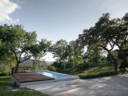 a swimming pool with a wooden deck and trees at Tapada do Sobral in Vilar de Ferreiros