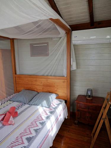 a bedroom with a bed with a canopy and a table at karureve in Deshaies