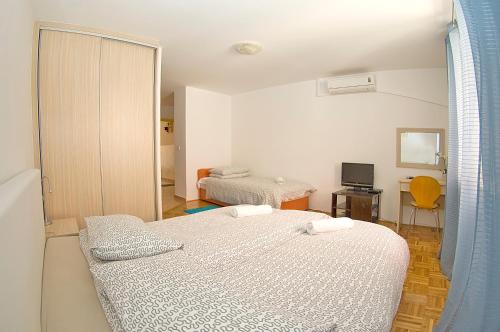a bedroom with two beds and a room with a television at Apartments Tomato 1 in Novigrad Istria