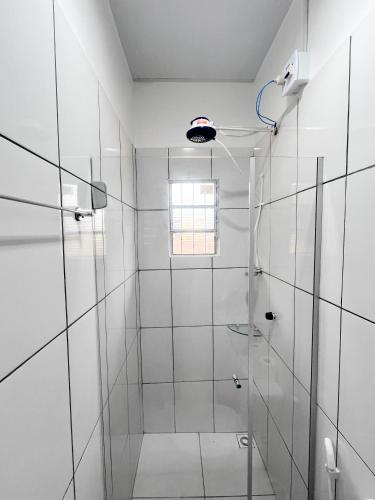 a white bathroom with a shower with a glass door at Pousada Marajó For You in Soure