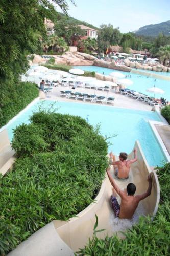 deux hommes sur un toboggan aquatique dans une piscine d'un complexe hôtelier dans l'établissement Appartement T2 dans résidence Les Restanques du Golfe à Grimaud, à Grimaud