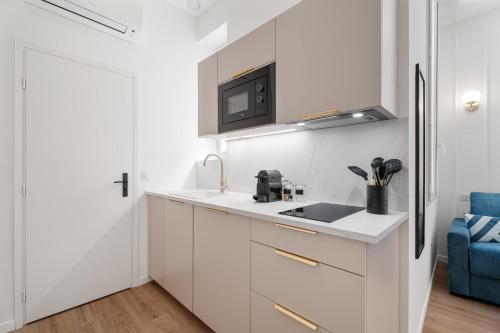 une cuisine blanche avec un évier et un micro-ondes dans l'établissement Studio Bella - Welkeys, à Cannes