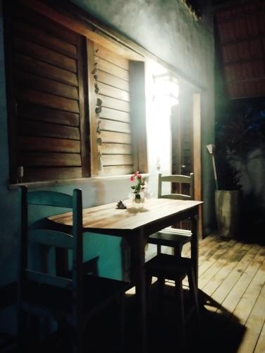 a wooden table with two chairs and a window at Chales Da Mata in Fortim