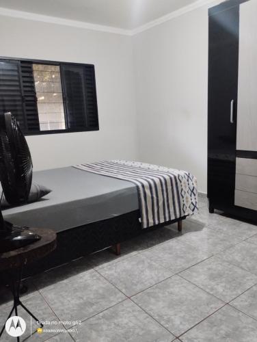 a bedroom with a bed and a chair and a window at Seu lugar de paz in Sarandi