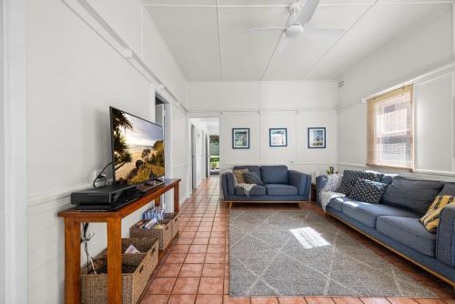 a living room with two couches and a flat screen tv at Mandys Cottage - 7 Memorial Avenue South West Rocks in South West Rocks