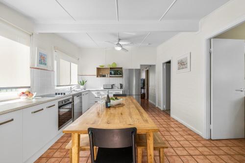 a large white kitchen with a wooden table and chairs at Mandys Cottage - 7 Memorial Avenue South West Rocks in South West Rocks
