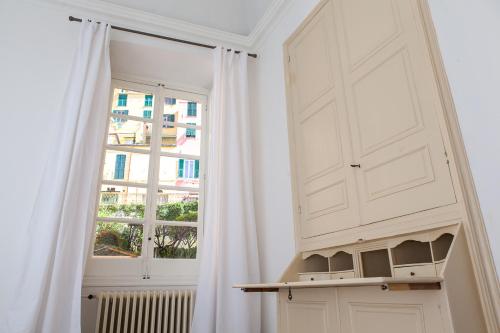 a white room with a window and a curtain at Casa Carducci - Spacious historical home close to the beach in Imperia