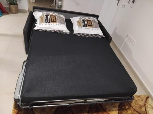 a black bed with pillows on top of it at appartement neuf au coeur du diamant in Le Diamant