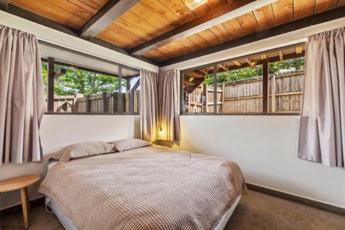 a bedroom with a bed and two windows at 43 Conical Hill Road in Hanmer Springs