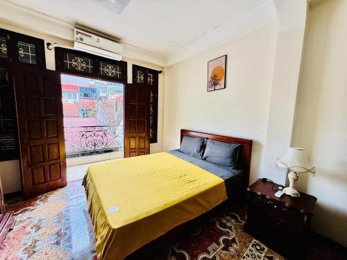 a bedroom with a bed with a yellow bedspread at IL Divo Hostel & Spa Hàng Đào in Hanoi