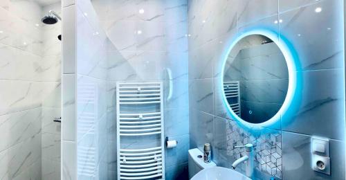 La salle de bains est pourvue d'un miroir rond et d'un lavabo. dans l'établissement Apartment Residence of Stade de France, à Saint-Denis