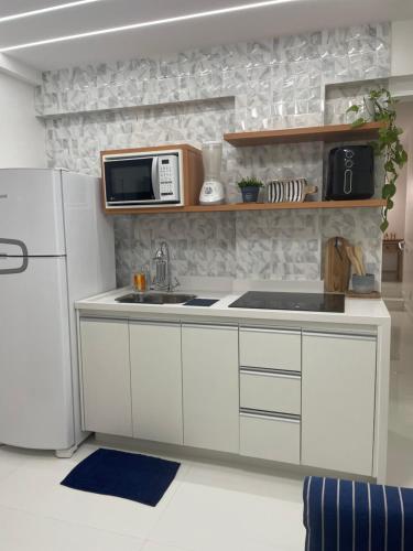 La cuisine est équipée d'un réfrigérateur blanc et d'un four micro-ondes. dans l'établissement BAHIA FLAT Apt 222, à Salvador