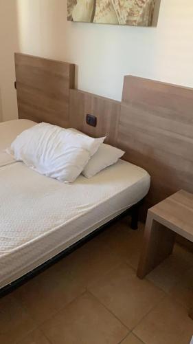 a bed with white sheets and pillows in a room at Villetta azzurra in Solfara Mare