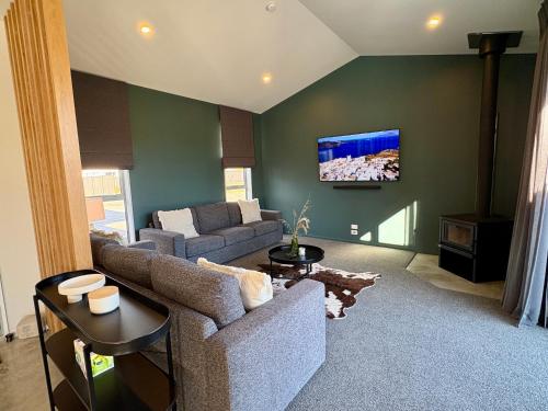 a living room with a couch and a tv on a wall at OHAU I Love 15 in Twizel