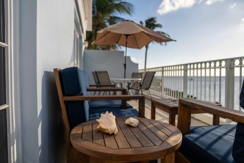 a table and chairs on a balcony with an umbrella at NEW Oceanfront Condo in George Town in George Town