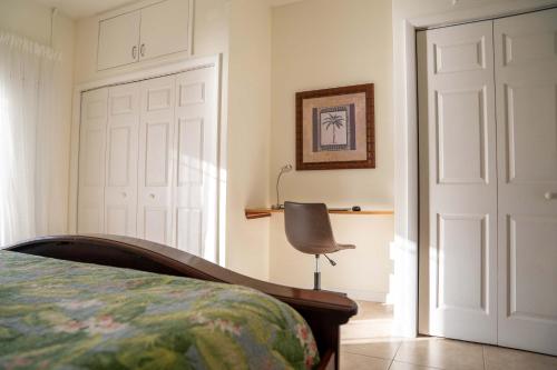 a bedroom with a bed and a chair next to a door at NEW Oceanfront Condo in George Town in George Town