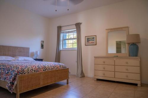 a bedroom with a bed and a dresser and a window at NEW Oceanfront Condo in George Town in George Town