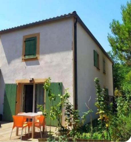 une maison avec une table et des chaises devant dans l'établissement Maison calme piscine pinède PMR parking, à Castries