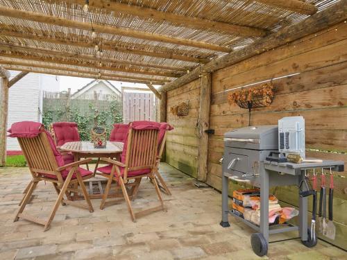 a patio with a table and chairs and a grill at Landsraderhöfke - 1 in Heijenrath