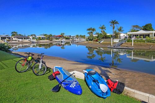 a bike and two kayaks are parked next to a body of water at Fabulous Canal-front Apartment in Mooloolaba