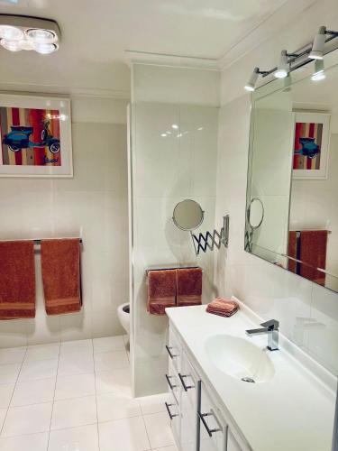 a white bathroom with a sink and a toilet at Centrally located Stylish Villa on the Hill in Albury