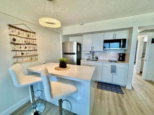 a kitchen with white cabinets and a island with chairs at Direct Oceanfront Coastal Bliss in Daytona Beach