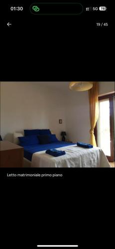 ein Schlafzimmer mit einem Bett mit blauen Laken und einem Fenster in der Unterkunft Villa Nausica in Terracina