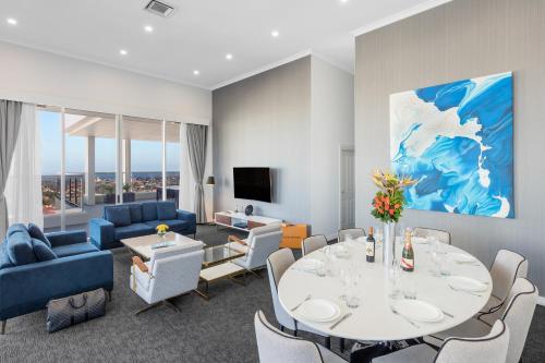 a living room with a white table and blue furniture at Meriton Suites Bondi Junction in Sydney